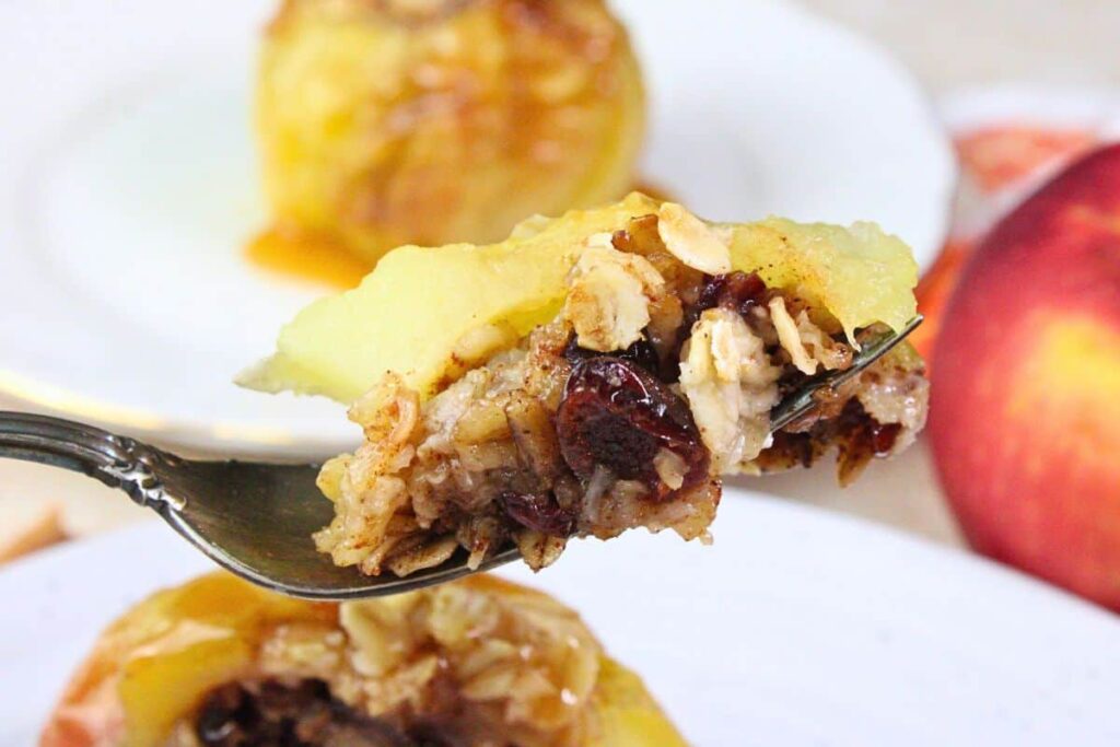holding up a fork with air fryer baked apple showing oats and cranberry filling