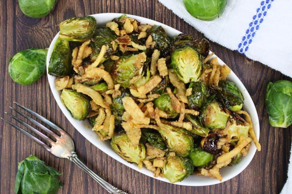 overhead view of red lobster brussel sprouts in an oval dish with more sprouts surrounding