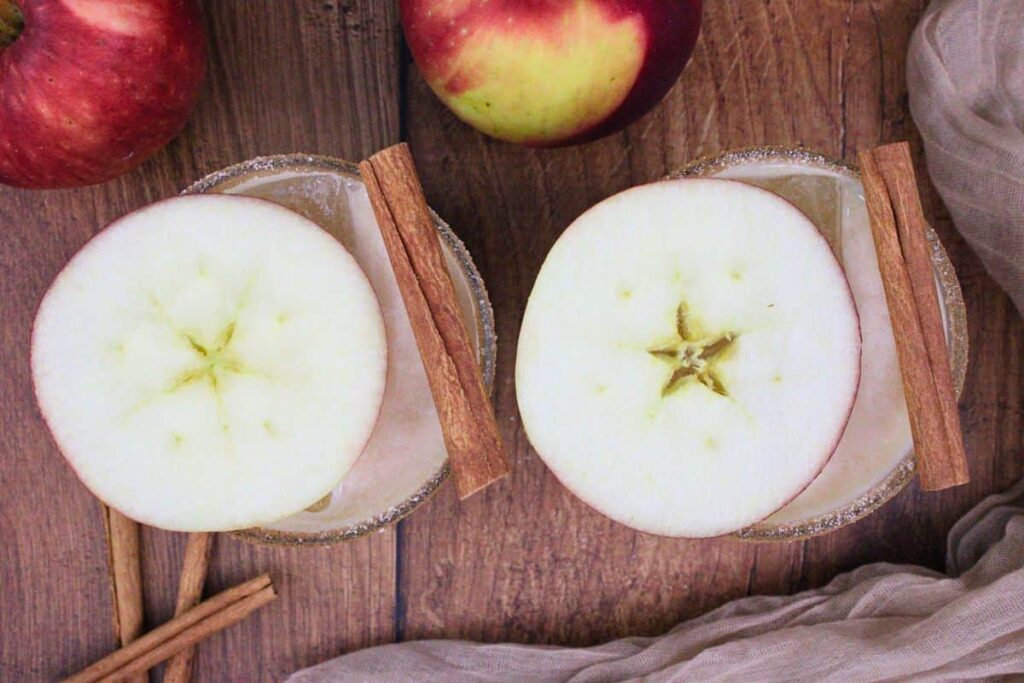 overhead view of two apple pie cocktails with apple and cinnamon stick garnish
