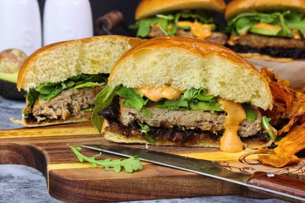 trader joes turkey burger cut in half with chipotle aioli dripping down plus arugala, avacado, and onion jam