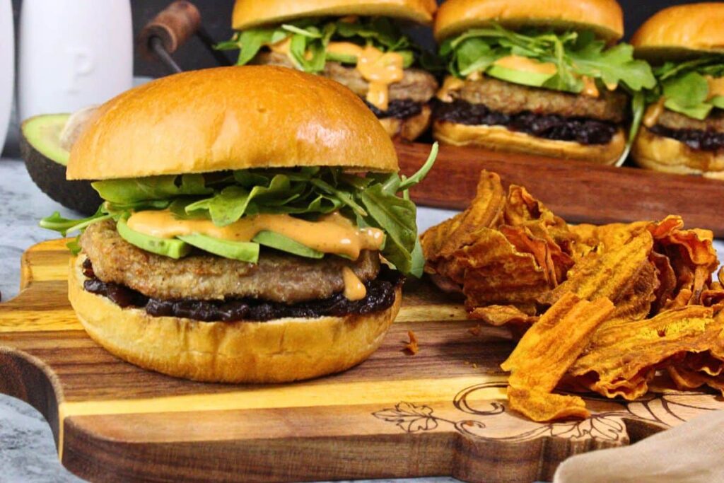 trader joes turkey burger with avacado, arugala, chipotle aioli, and caramelized onion jam on a brioche bun next to sweet potato chips