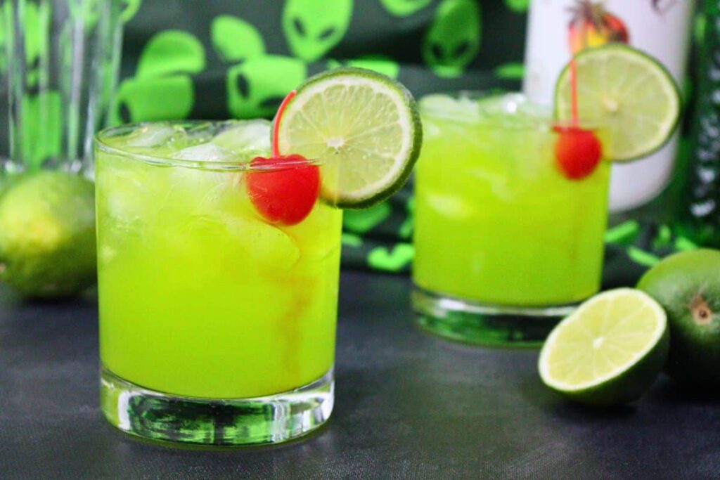 two alien secretion drinks with lime and cherry garnish in front of alien cloth