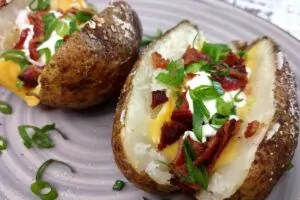 air fryer baked potato topped with bacon, cheese, sour cream, and onions