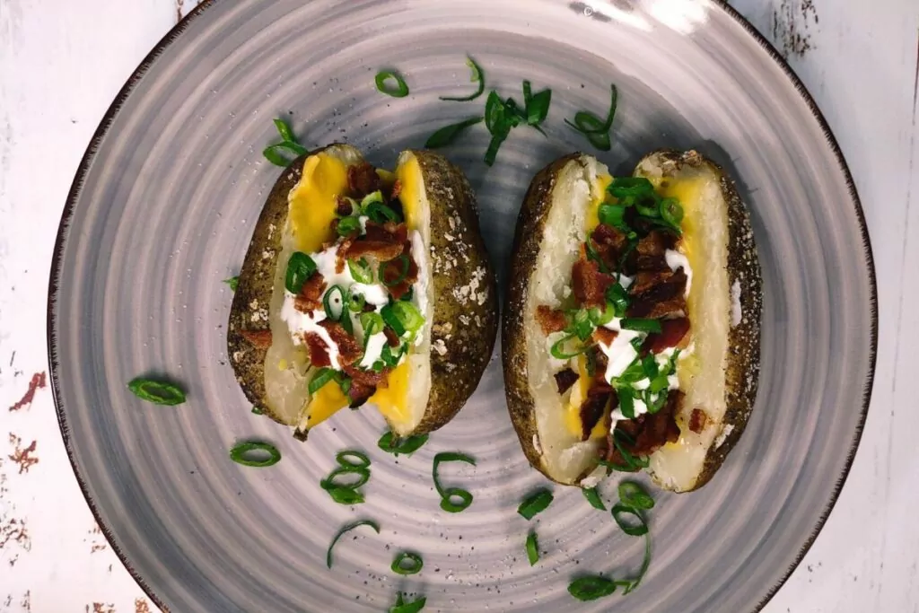 overhead view of 2 loaded baked potatoes on a plate