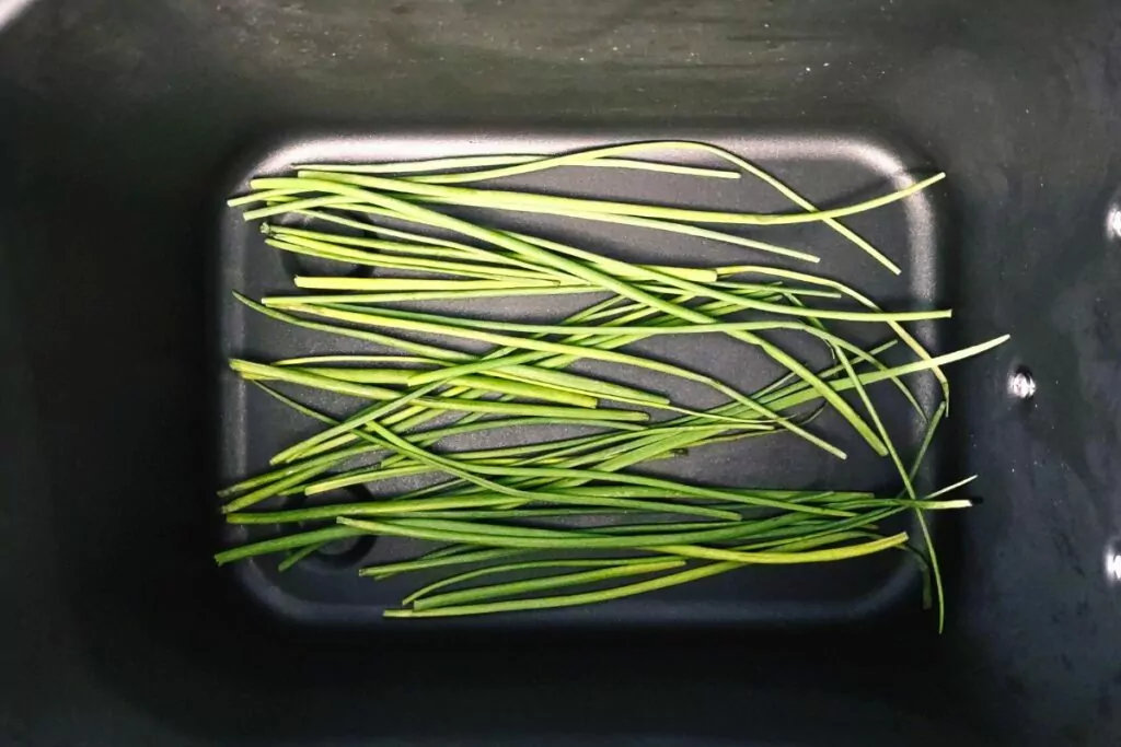 spread fresh chives on bottom of air fryer basket