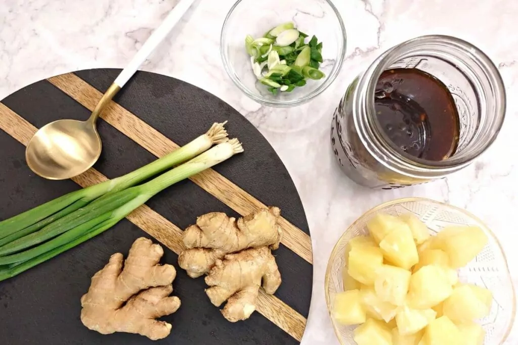 overhead view of teriyaki sauce in a jar with fresh ginger, scallions, and pineapple