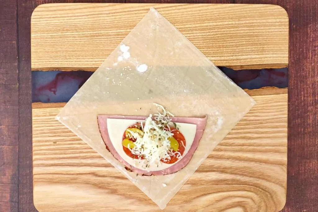 add ham, cheese, pepperoni, and other ingredients to egg roll wrapper