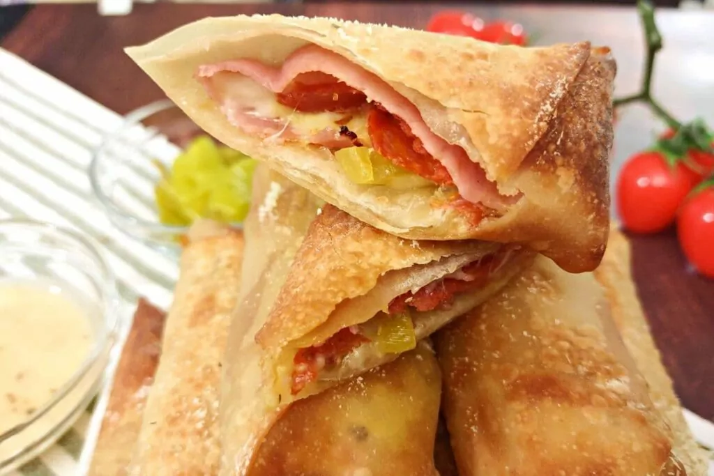 sliced antipasto egg roll sitting on top of uncut rolls