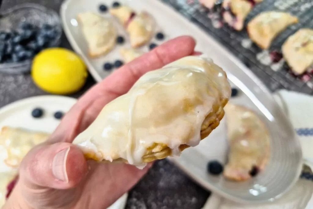 holding up a glazed blueberry hand pie made in the air fryer