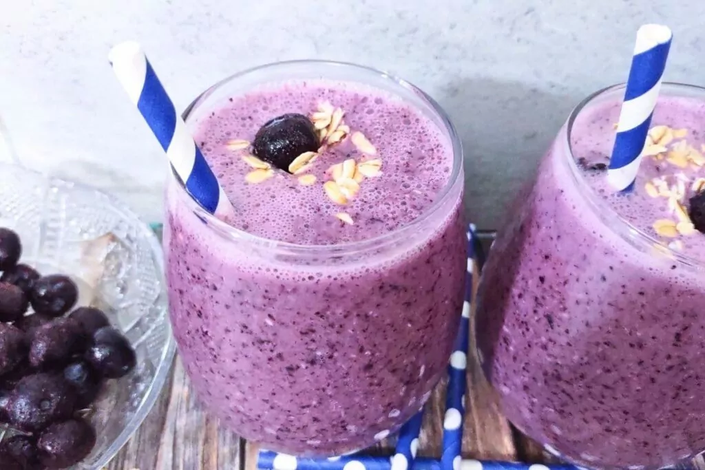 three quarter view of a blueberry pie smoothie with some blueberry and oats sprinkled on top