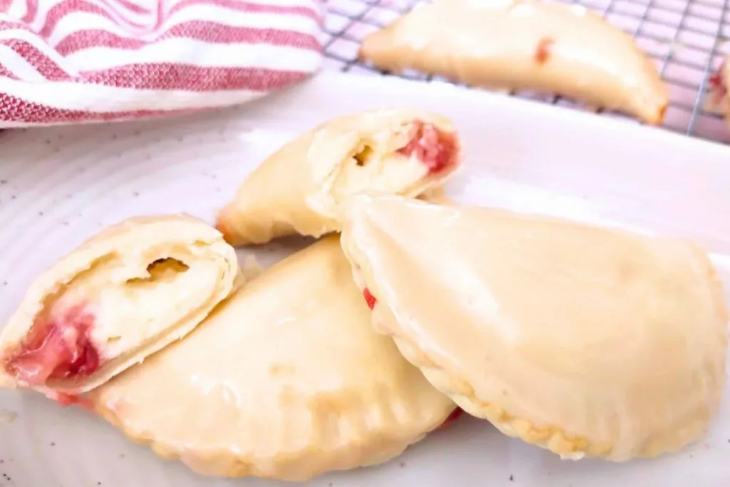 strawberry cream hand pies cut in half and stacked on a plate