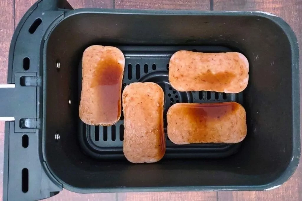 brush spam slices with teriyaki sauce in air fryer basket
