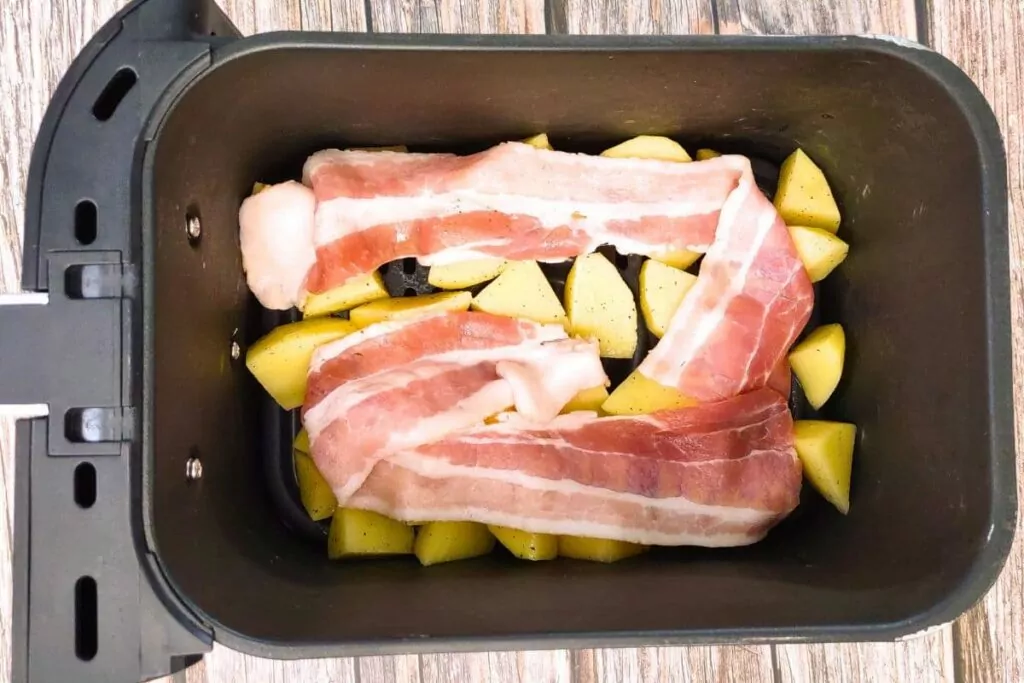 place seasoned potatoes in air fryer basket along with bacon strips