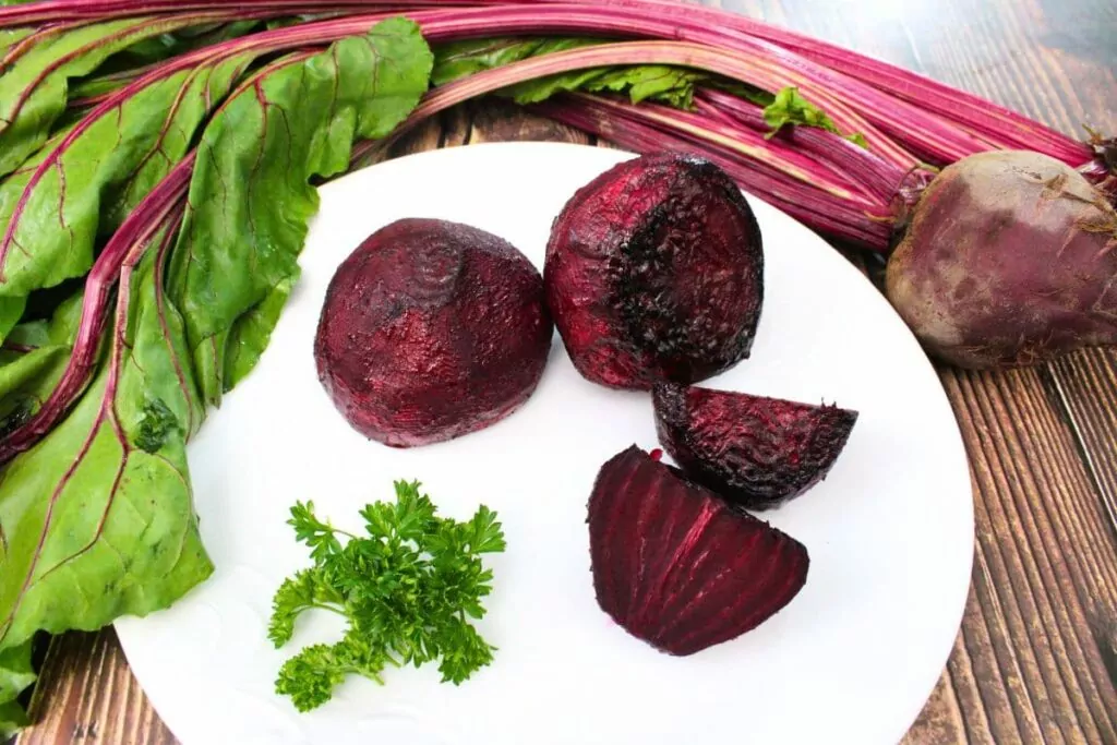 delicious air fryer whole roasted beets on a plate with fresh raw beets above