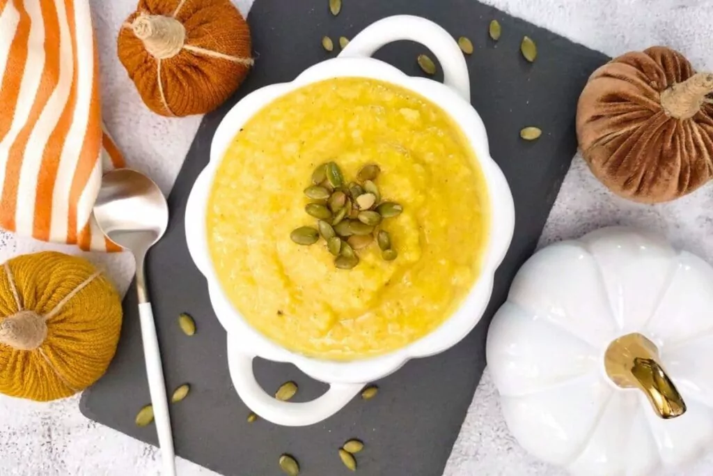 overhead view of air fryer pumpkin soup in a ceramic bowl with pepitas