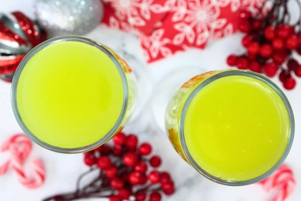 overhead view of two grinch mimosas surrounded by christmas decor