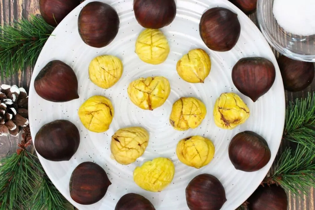 overhead view of warm microwave chestnuts on a plate surrounded by fresh ones