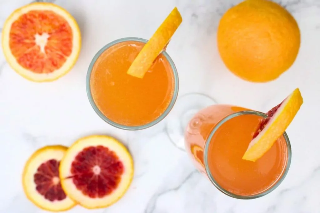 overhead view of two blood orange french 75 drinks in champagne flutes