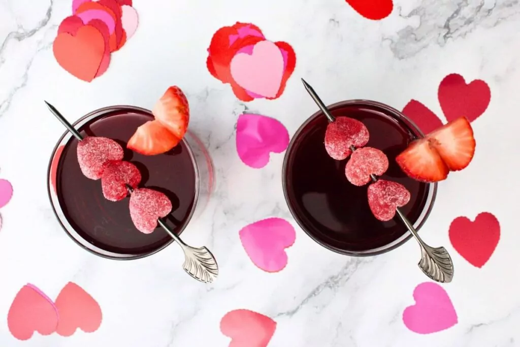 overhead view of two love potion cocktails with heart candies and decorations