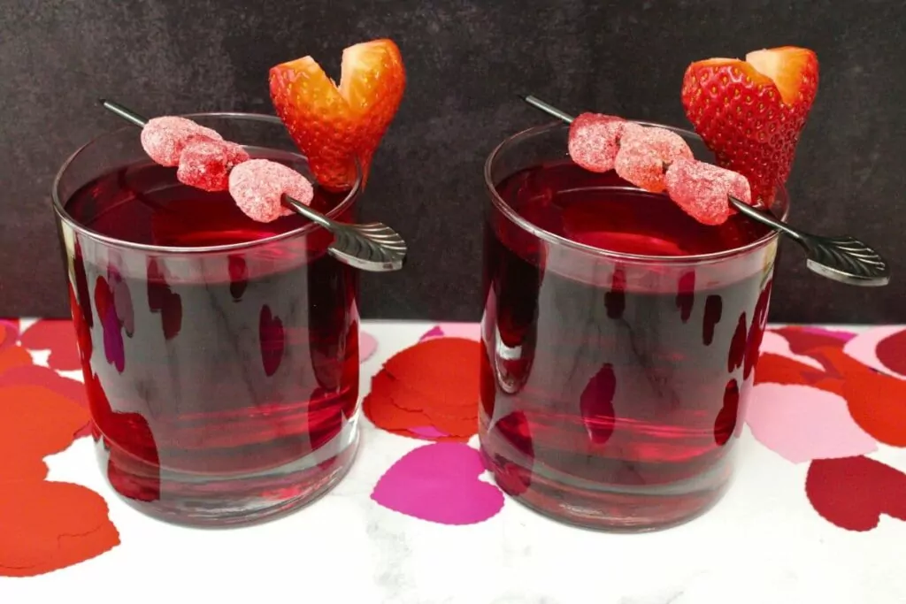 two love potion cocktails with candy gummy skewers against a dark background