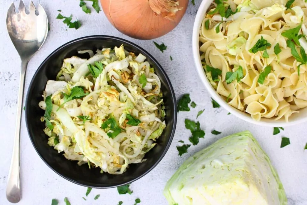 overhead view of air fryer cabbage and onions in a bowl next to a bowl of haluski