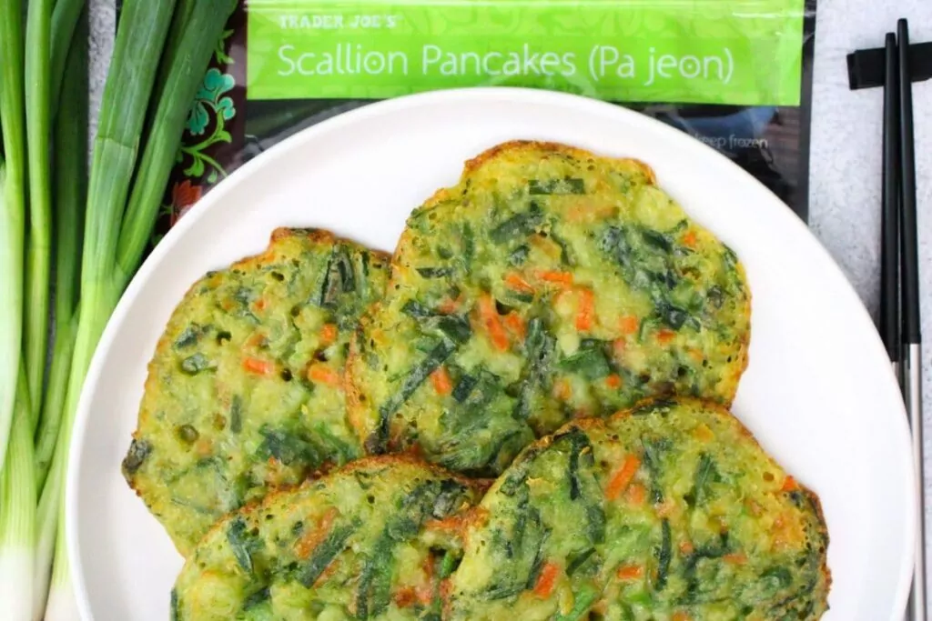 overhead view of air fryer trader joes scallion pancakes on a plate in front of packaging