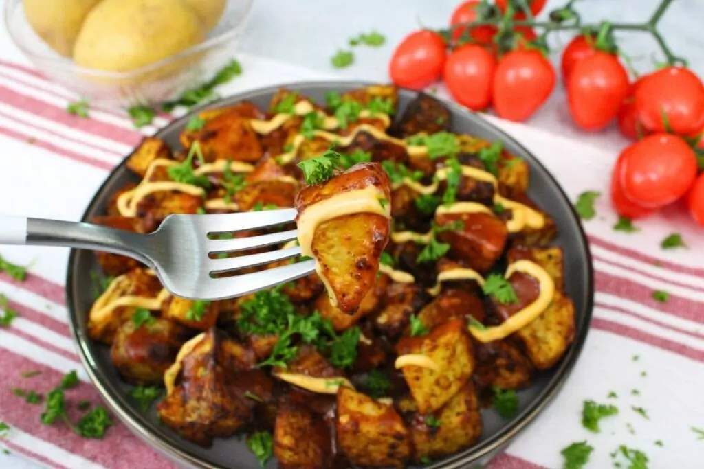 fork holding up a piece of air fryer patatas bravas