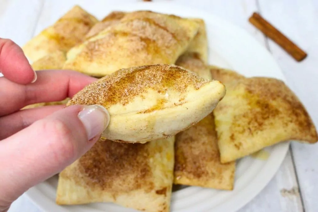 holding up a fluffy air fryer sopapillas with cinnamon sugar on top