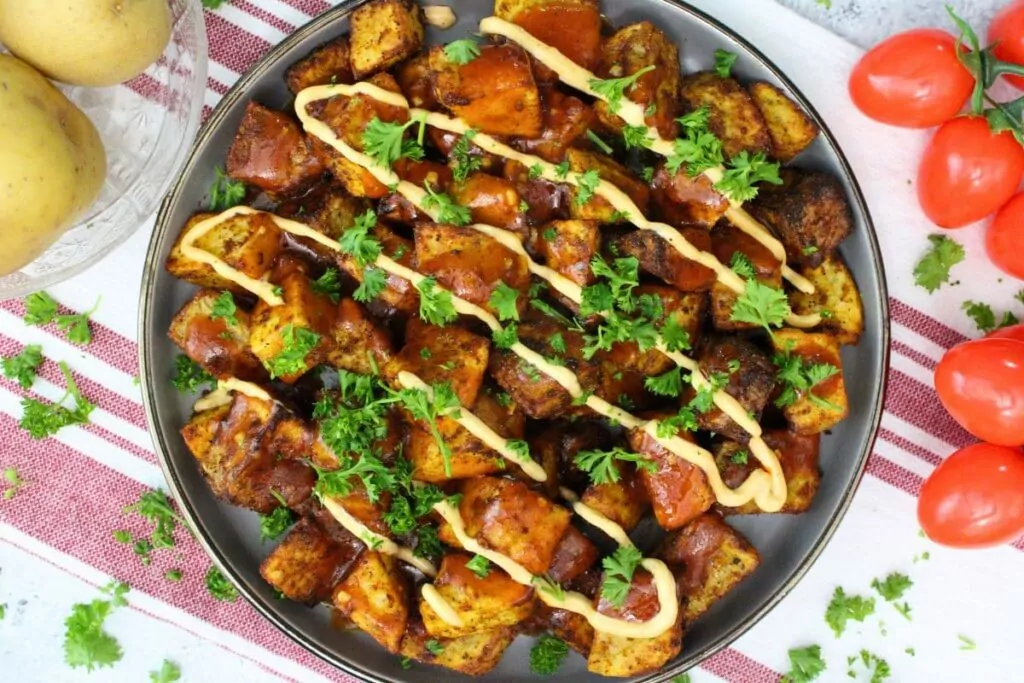 overhead view of a plate of air fryer patatas bravas with a drizzle of spicy mayo