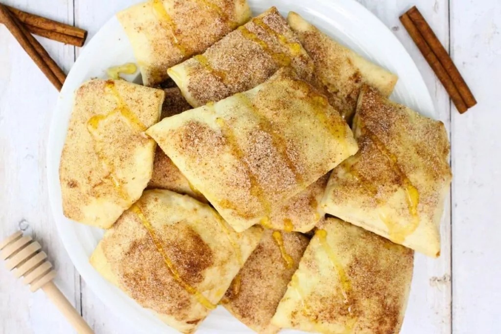 overhead view of air fryer sopapillas on a plate with cinnamon sugar and drizzled honey