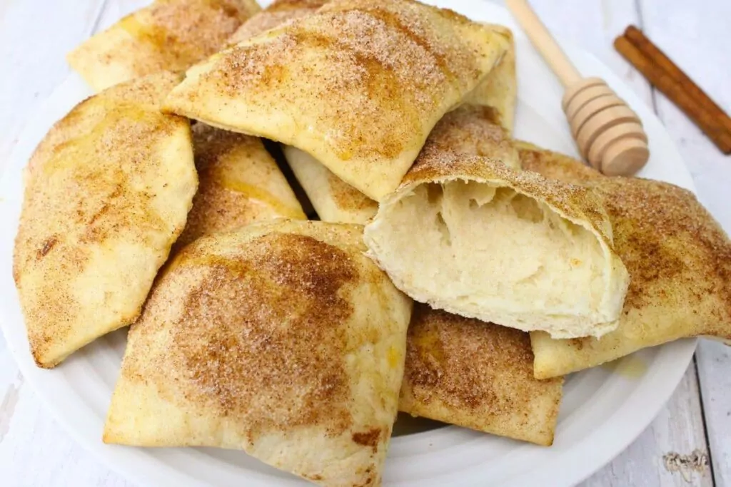 plate of air fryer sopapillas with one cut in half to show the insides