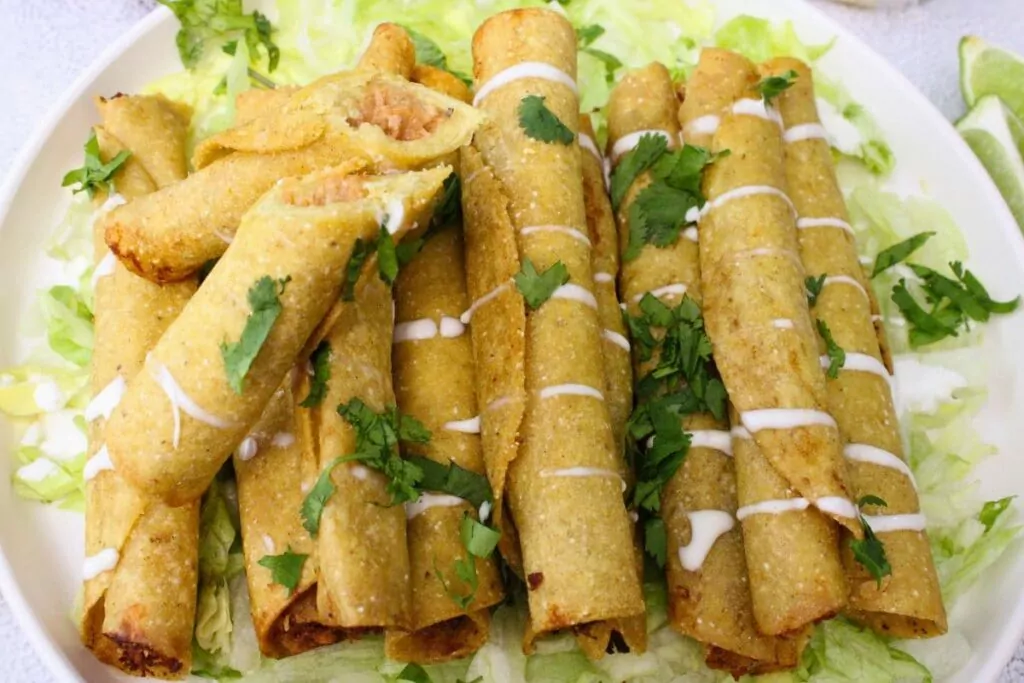 trader joes chicken taquitos stacked on a plate with one cut in half