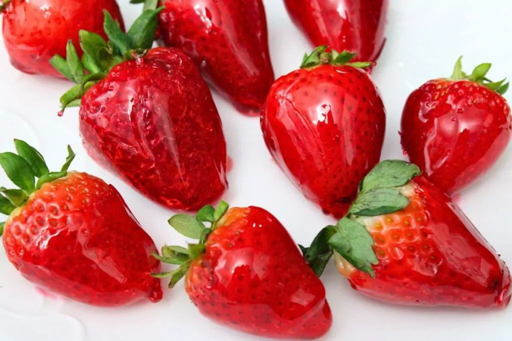 closeup view of several jolly rancher coated strawberries on a plate