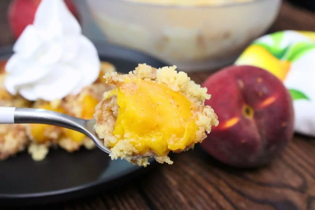 holding up a spoonful of peach cobbler made in the microwave