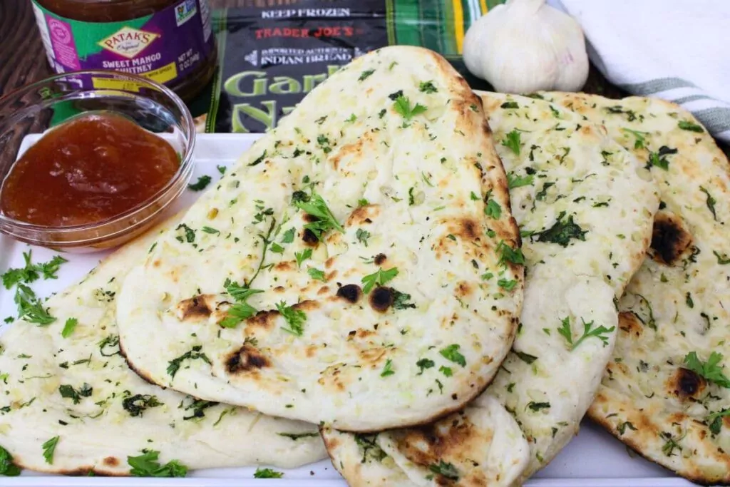 four slices of air fryer trader joes garlic naan across a plate with mango chutney dipping sauce