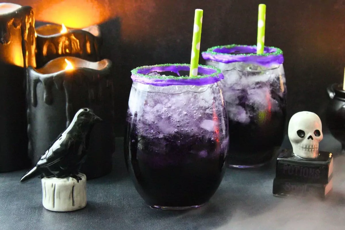 two halloween drunk witch cocktails surrounded by halloween decorations and smoke