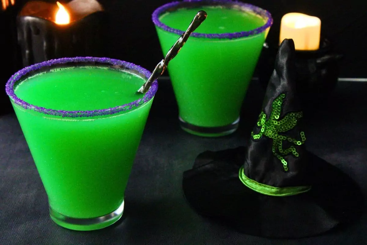two broadway inspired wicked witch cocktails next to a small witch hat