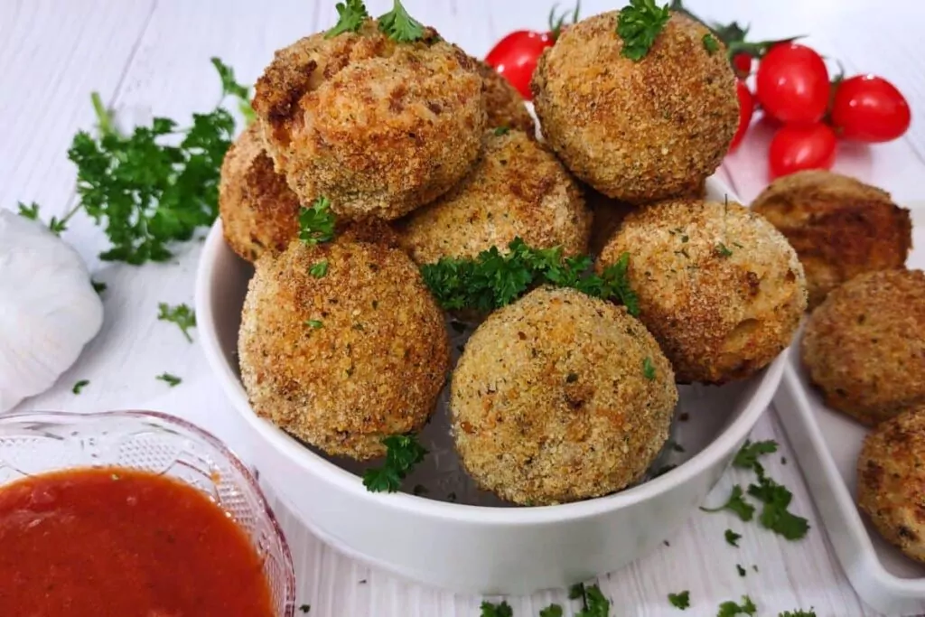 air fryer mozzarella arancini in a bowl with marinara on the side