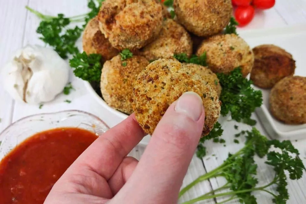 holding up an air fried arancini rice ball