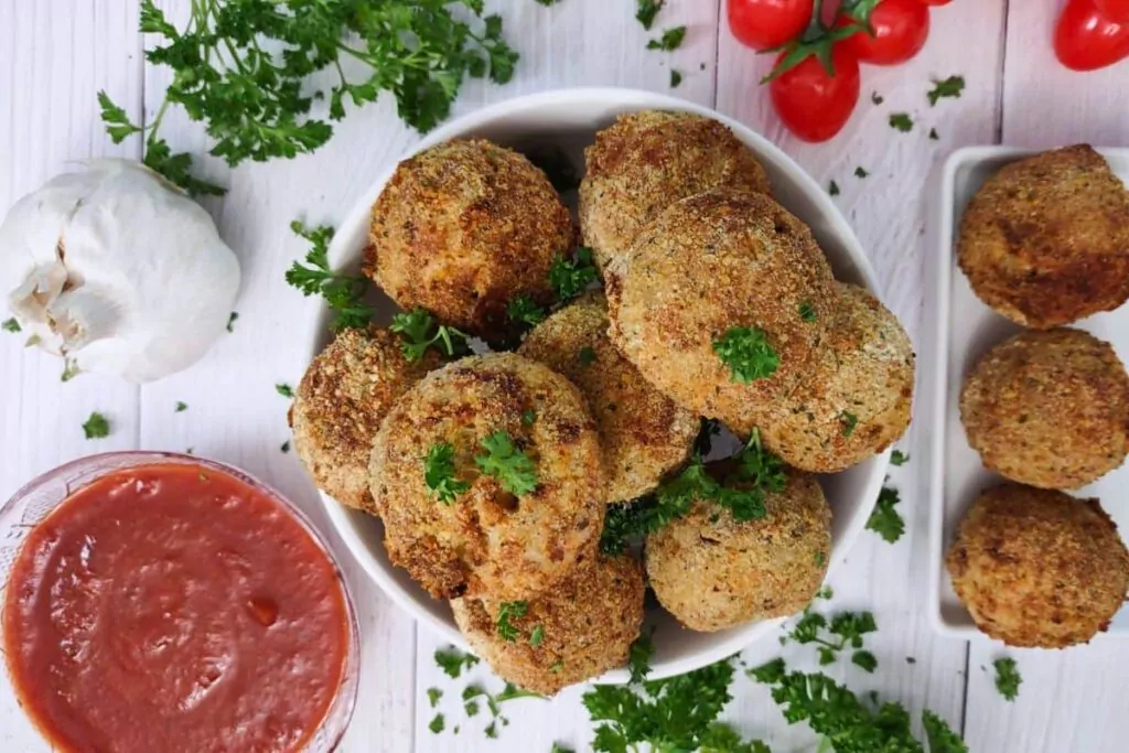 overhead view of arancini rice balls with marinara dipping sauce on the side