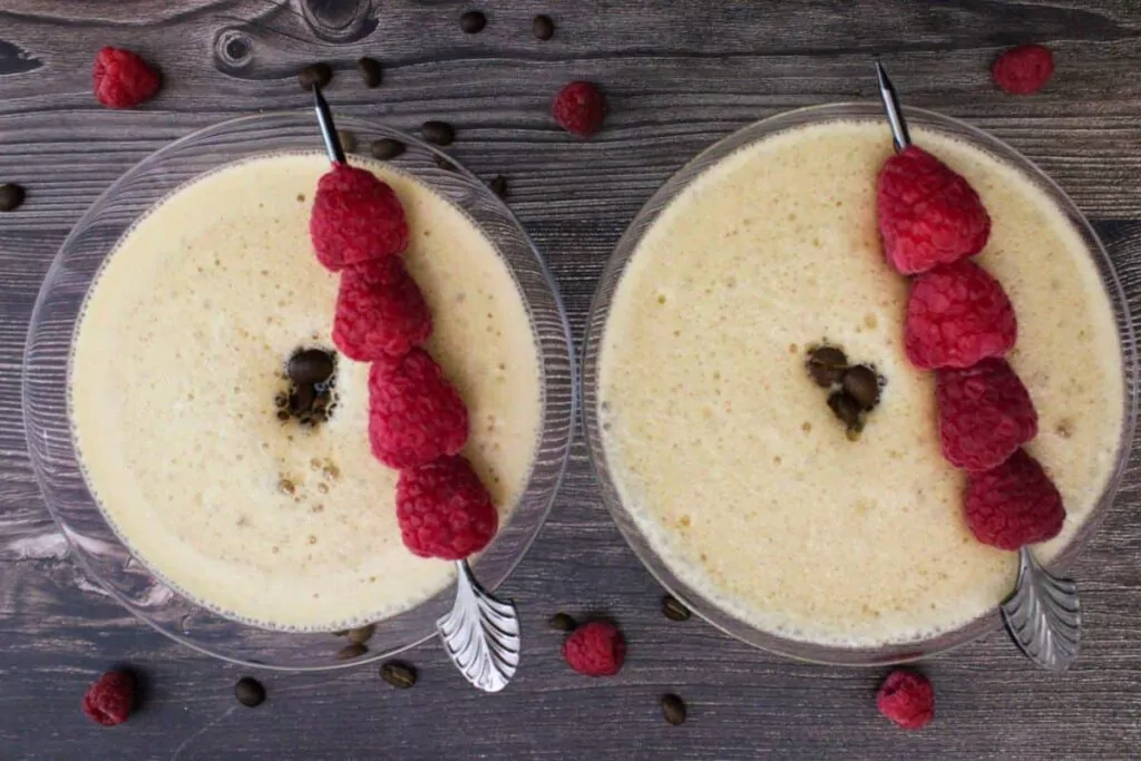 overhead view of two raspberry espresso martinis with raspberry skewers and three coffee beans each