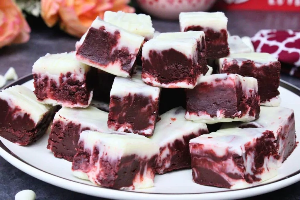 squares of microwave red velvet fudge stacked up on a white plate