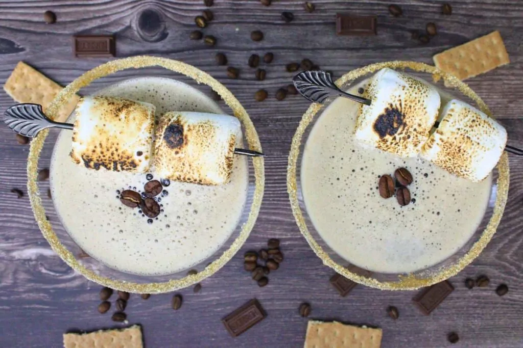 overhead view of two smores espresso martinis with toasted marshmallows and espresso beans surrounded by graham crackers and more beans