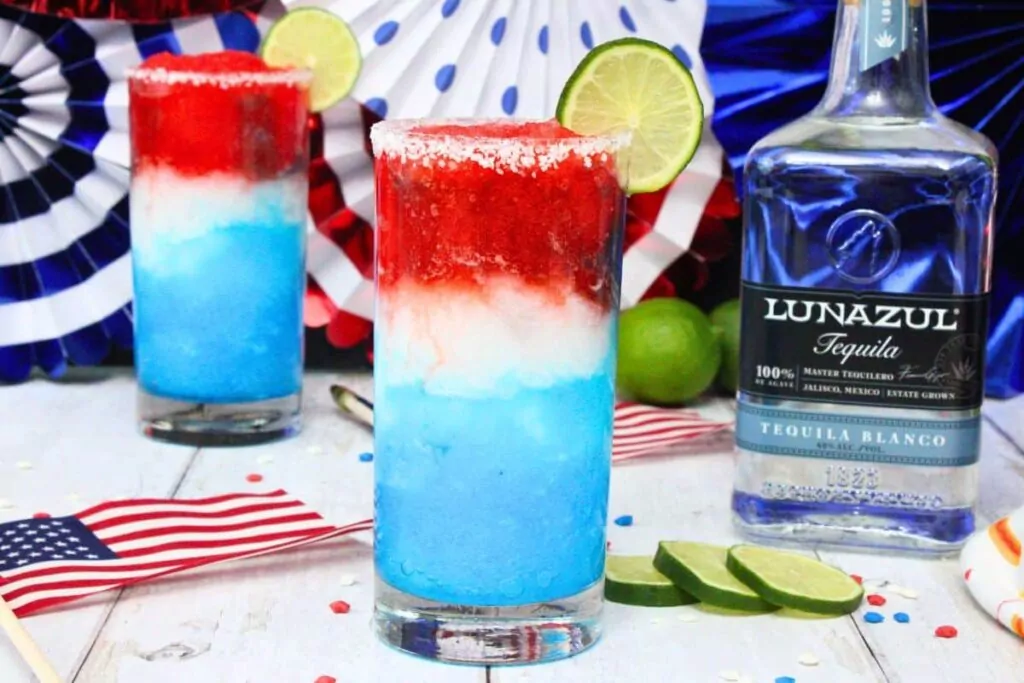 red white and blue margarita with next to tequila bottle and surrounded by patriotic decorations