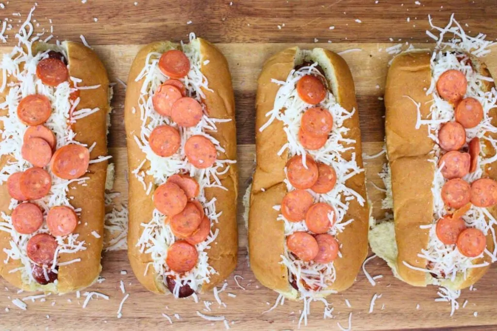 top cooked hot dogs with pizza sauce, italian seasoning, mozzarella cheese, and mini pepperoni