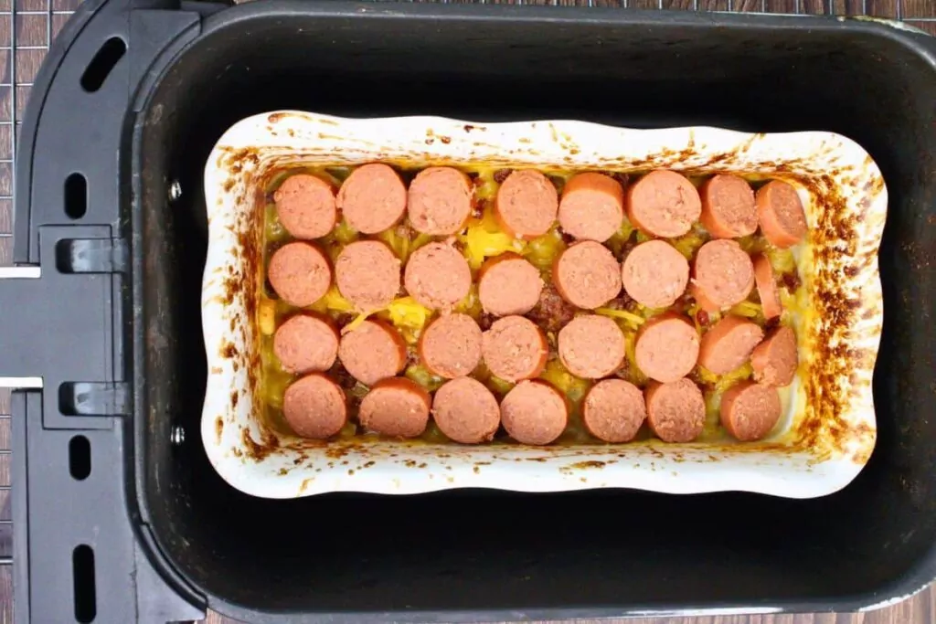 top mac and cheese with hot dog slices and continue cooking
