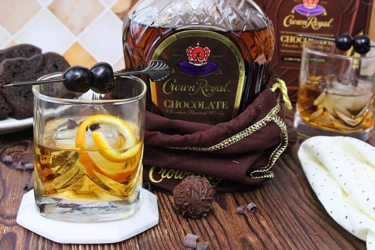 chocolate old fashioned next to chocolate crown royal bottle on a wooden table
