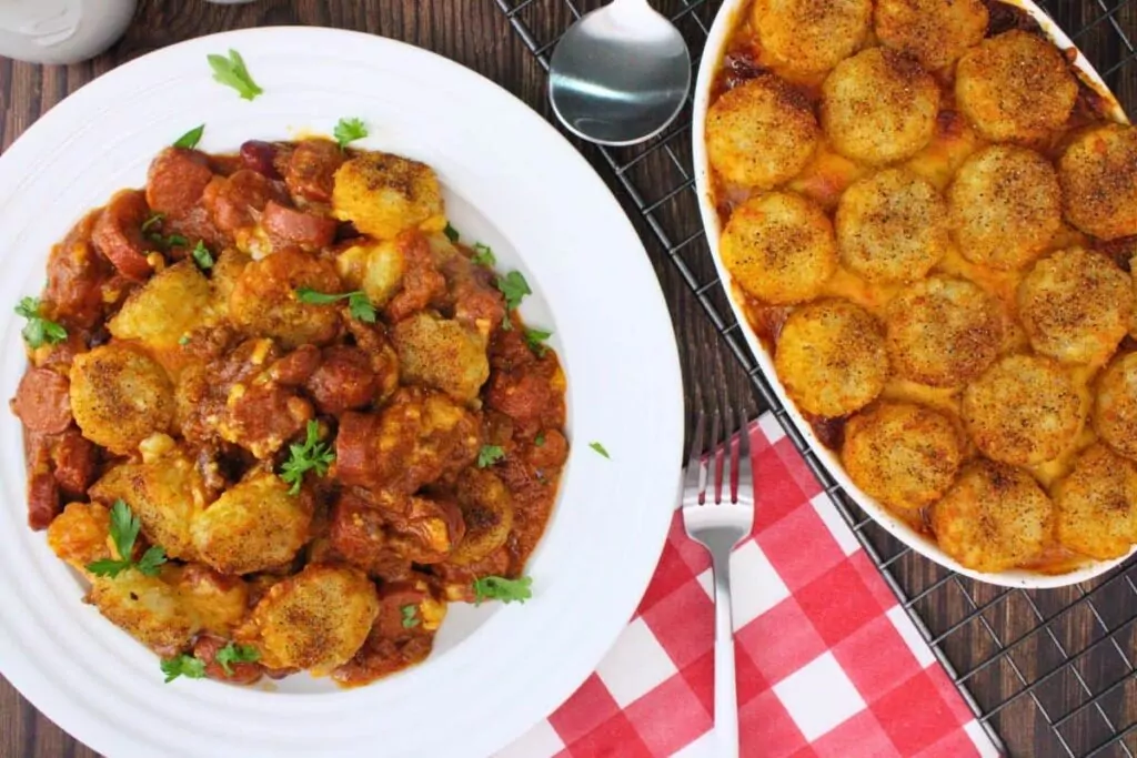 overhead view of chili cheese hot dog casserole on a plate next to a casserole dish with more