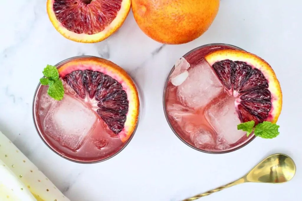 overhead view of two blood orange gin fizz cocktails garnished with blood orange slices