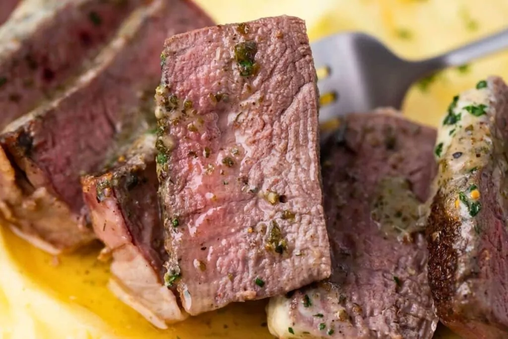 closeup view of juicy and tender slices of bacon wrapped filet with herb butter